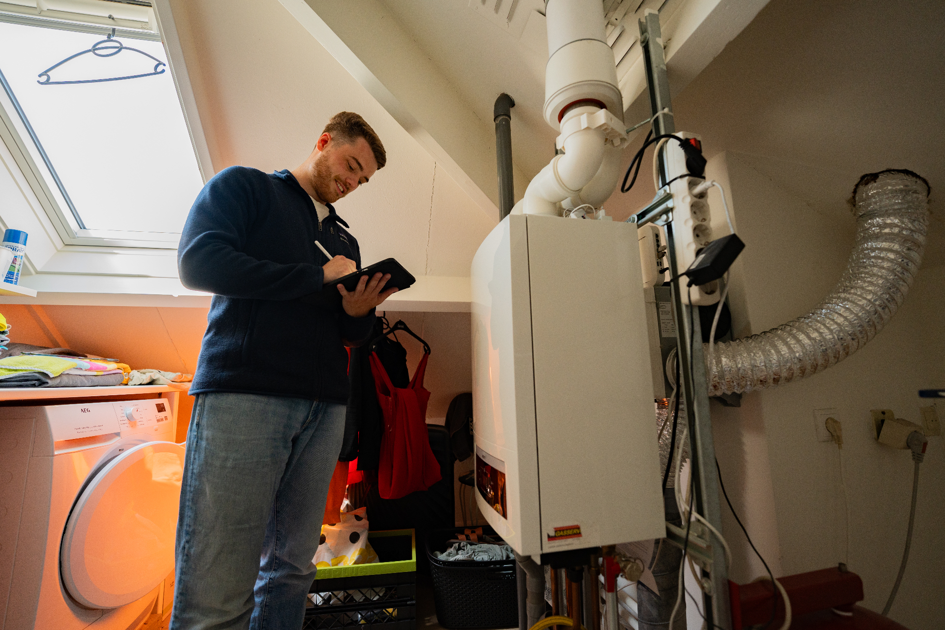 NoGasCo-adviseur inspecteert een CV-installatie op zolder